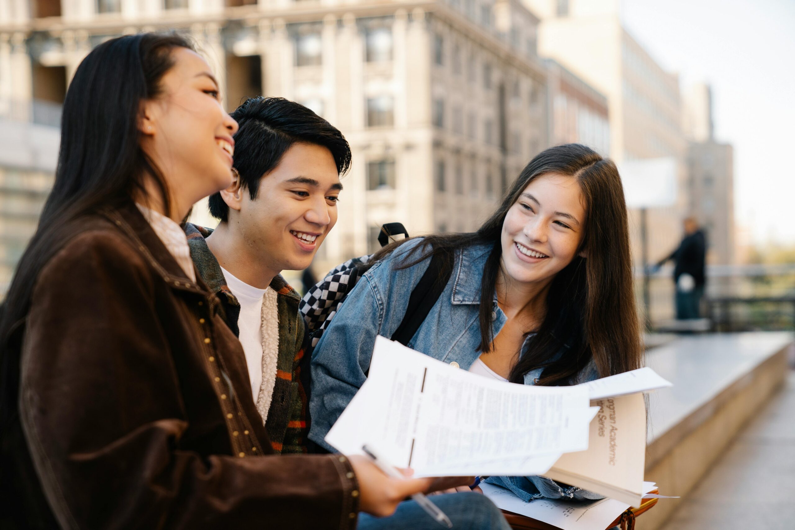 Three young adults sitting on campus benches, enjoying their conversation.