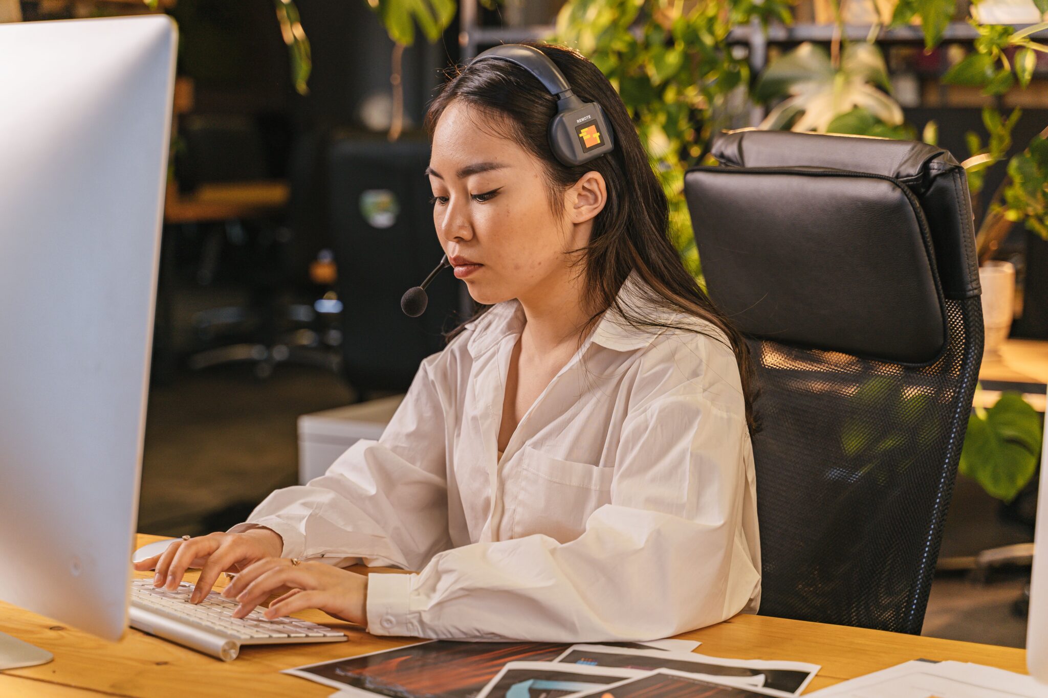 Young Asian woman using a computer at a desk in a modern office environment.